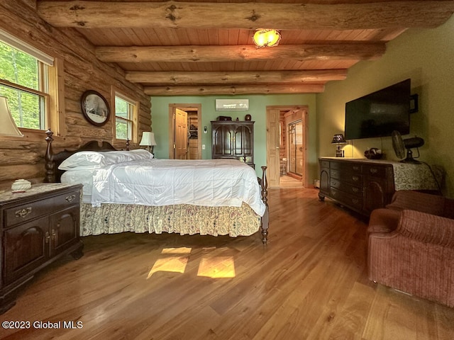 bedroom with log walls, a spacious closet, beam ceiling, and wood-type flooring