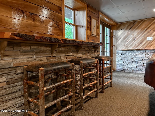 bar featuring wood walls and dark colored carpet