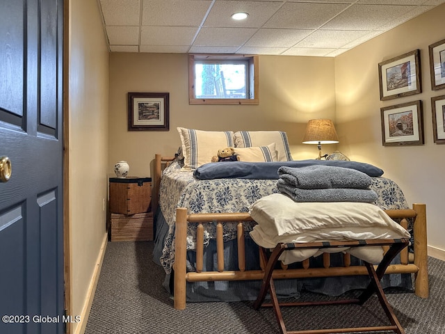 bedroom with dark colored carpet and a drop ceiling