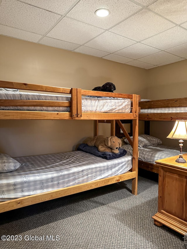 unfurnished bedroom with a paneled ceiling and dark colored carpet