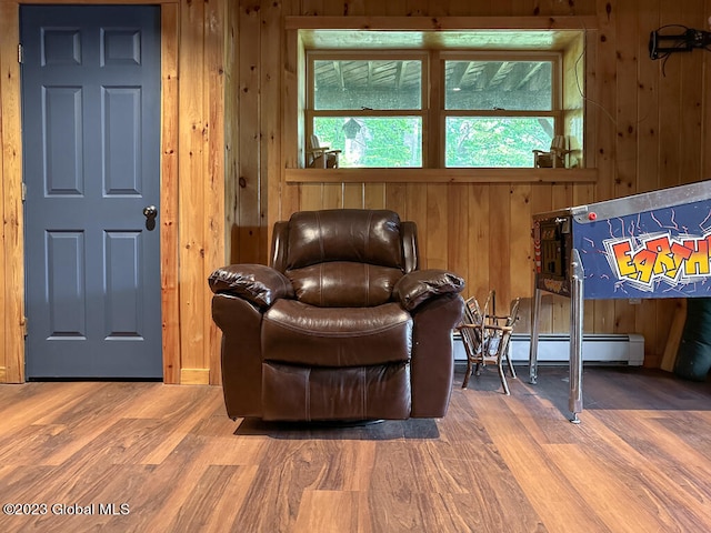 sitting room with wooden walls, baseboard heating, and dark wood-type flooring