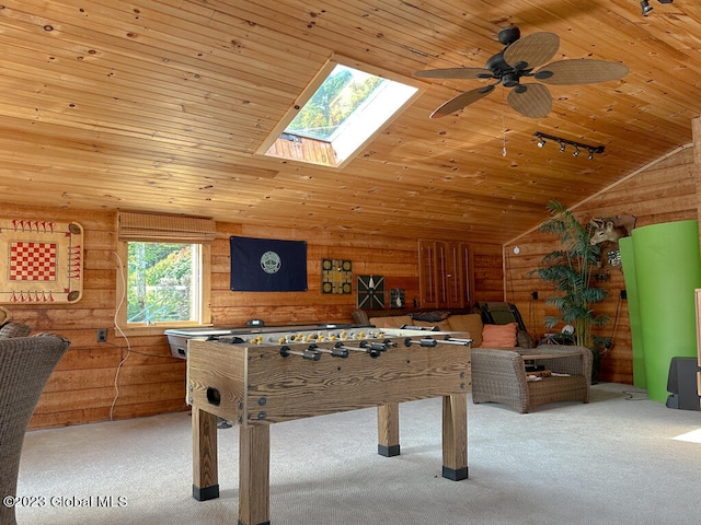 playroom featuring ceiling fan, vaulted ceiling with skylight, log walls, wooden ceiling, and light colored carpet