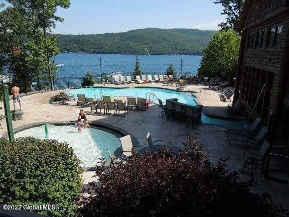 view of pool featuring a water view and a patio