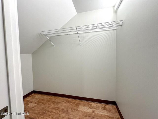 spacious closet featuring light wood-type flooring and lofted ceiling