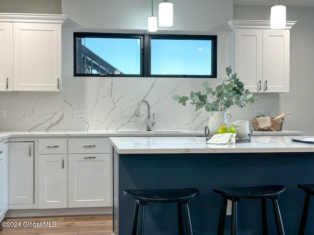 kitchen with white cabinets, decorative light fixtures, and plenty of natural light