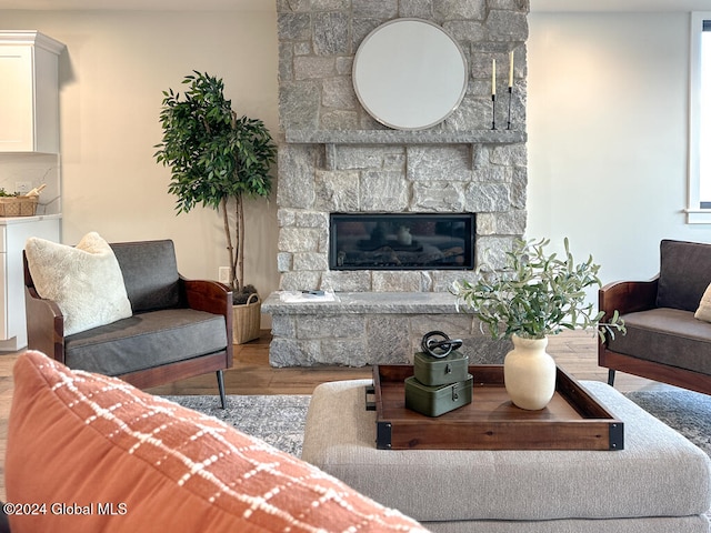 living room featuring a stone fireplace and light wood-type flooring