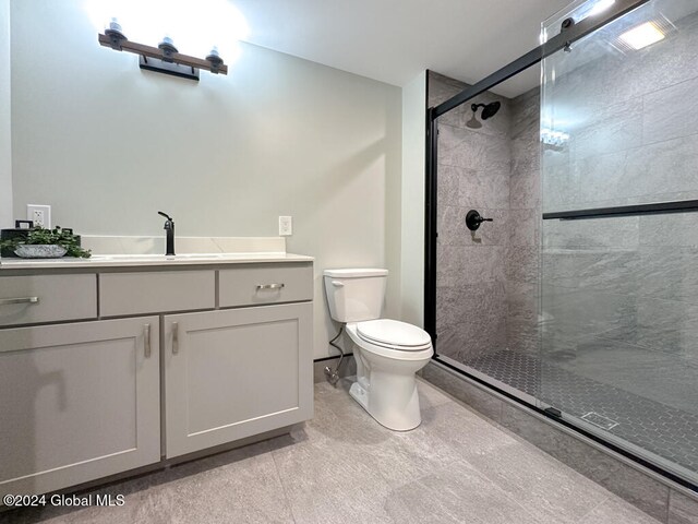 bathroom featuring tile patterned flooring, toilet, vanity, and walk in shower