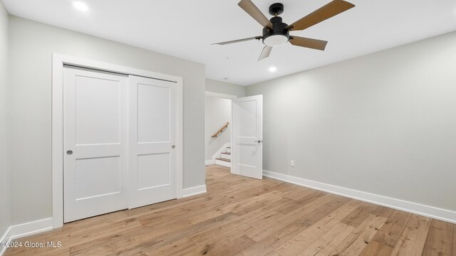 unfurnished bedroom with light hardwood / wood-style flooring, a closet, and ceiling fan