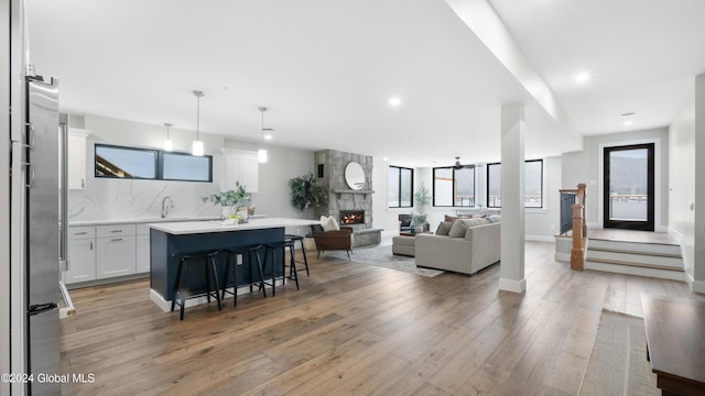 living room featuring ceiling fan, a stone fireplace, and light hardwood / wood-style flooring