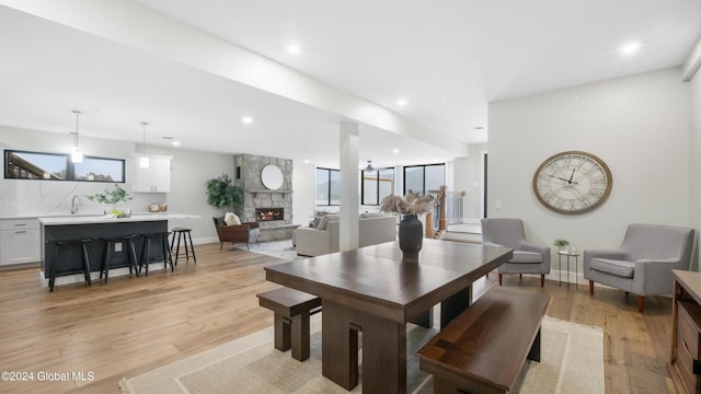 dining room featuring light hardwood / wood-style floors, a stone fireplace, plenty of natural light, and sink