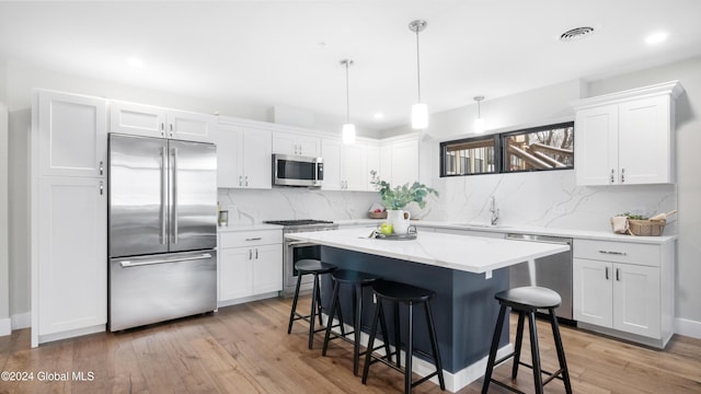 kitchen featuring white cabinets, pendant lighting, backsplash, and high end appliances