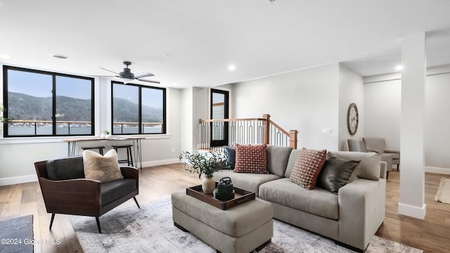 living room featuring a mountain view, ceiling fan, and light wood-type flooring