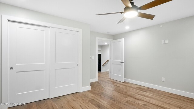 unfurnished bedroom with ceiling fan, a closet, and light wood-type flooring