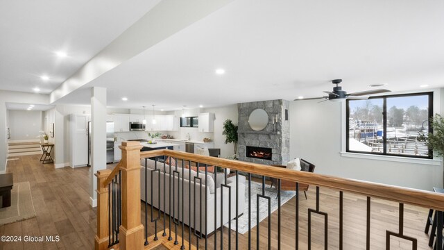 living room with ceiling fan, a fireplace, and light hardwood / wood-style flooring