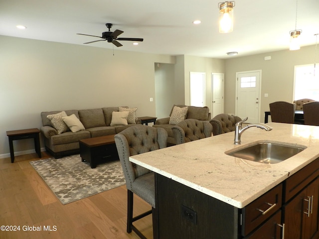 interior space featuring light stone counters, light hardwood / wood-style floors, ceiling fan, and sink