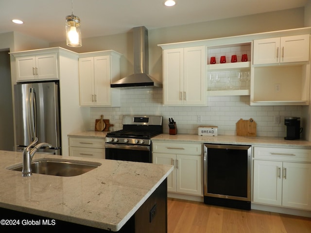 kitchen with stainless steel appliances, decorative light fixtures, wall chimney exhaust hood, backsplash, and light wood-type flooring