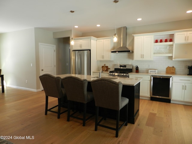 kitchen featuring pendant lighting, a kitchen breakfast bar, appliances with stainless steel finishes, wall chimney exhaust hood, and light wood-type flooring