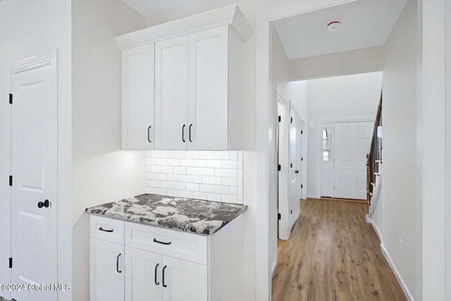 kitchen with backsplash, dark stone counters, light hardwood / wood-style floors, and white cabinets