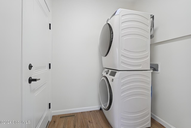 washroom featuring hardwood / wood-style floors, stacked washer and clothes dryer, and washer hookup