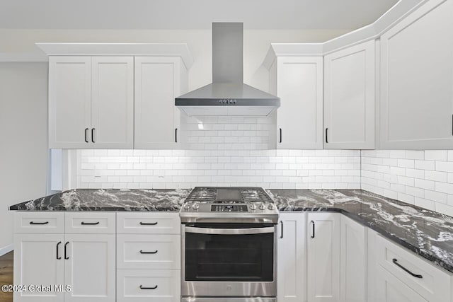 kitchen with gas range, white cabinets, wall chimney range hood, tasteful backsplash, and dark stone countertops