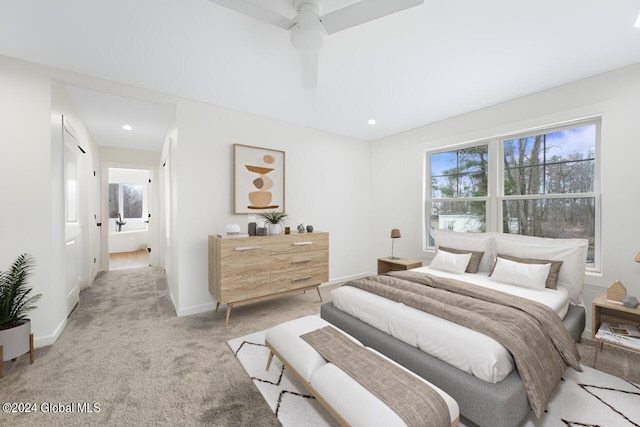 bedroom with light colored carpet, ceiling fan, and ensuite bath