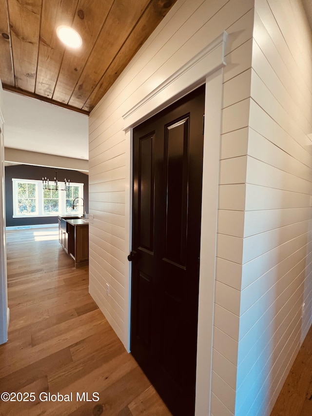 hall featuring wooden walls, light hardwood / wood-style flooring, and wooden ceiling