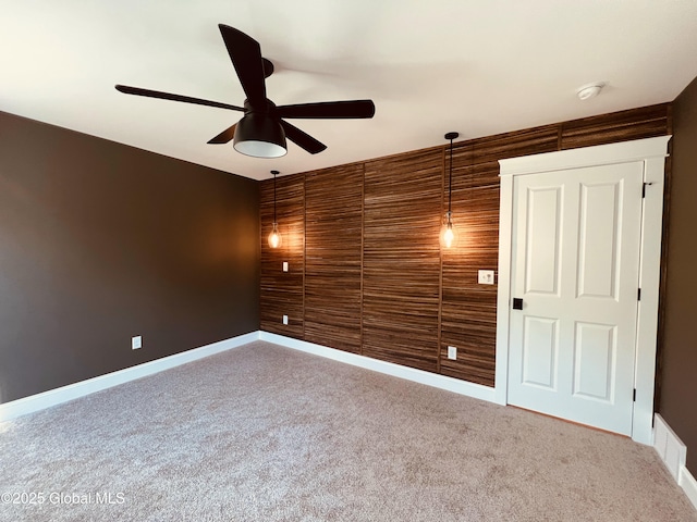 spare room with wood walls, ceiling fan, and carpet flooring