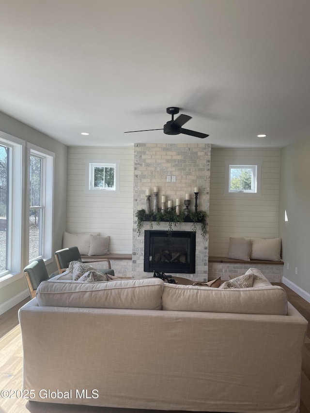 living room featuring a fireplace, light hardwood / wood-style floors, and ceiling fan