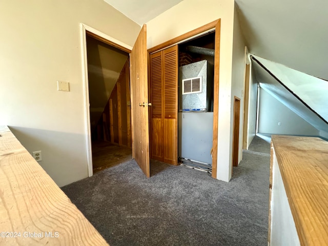 unfurnished bedroom with lofted ceiling, a closet, and dark colored carpet