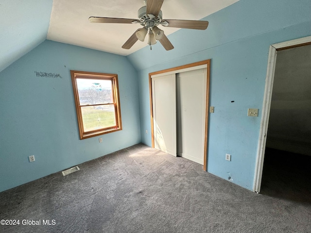 unfurnished bedroom with ceiling fan, lofted ceiling, dark colored carpet, and a closet