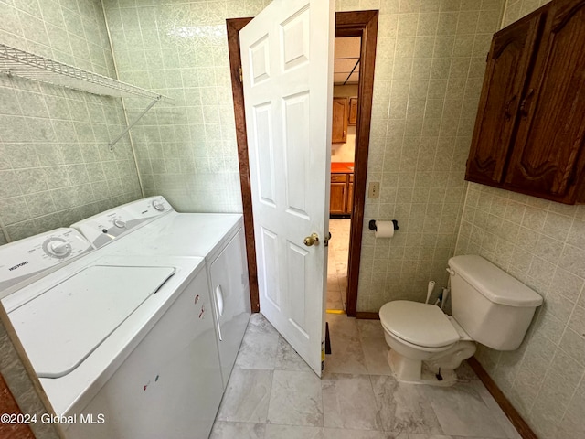 laundry room featuring tile walls, washing machine and dryer, and light tile floors