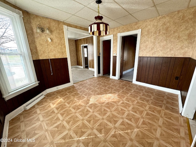 spare room with baseboard heating, a paneled ceiling, and light parquet flooring