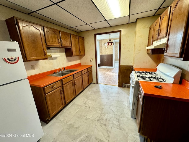 kitchen with sink, white appliances, a paneled ceiling, and light tile floors