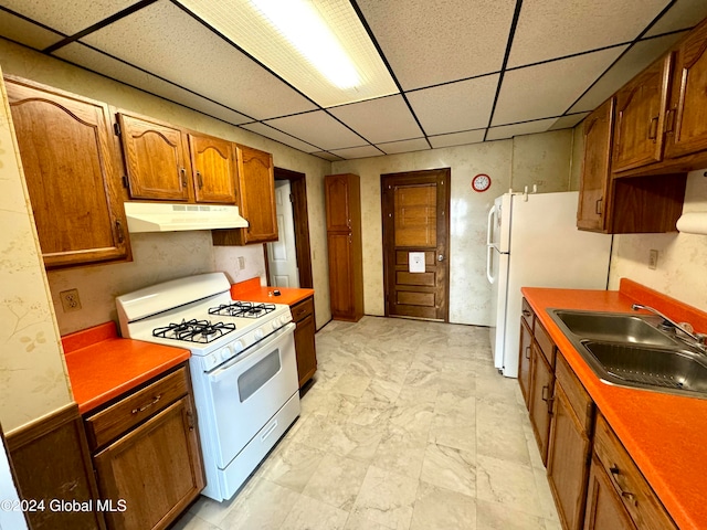 kitchen featuring sink, white appliances, a drop ceiling, and light tile floors