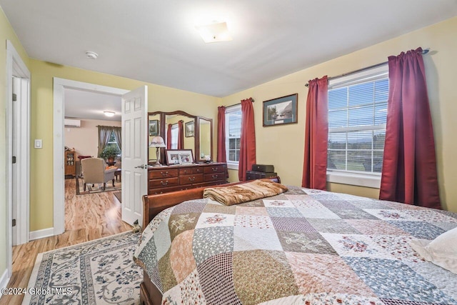 bedroom featuring a wall unit AC and light hardwood / wood-style floors