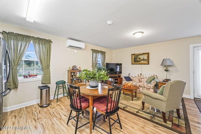 dining space with an AC wall unit and light hardwood / wood-style flooring