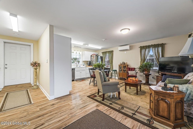 living room with an AC wall unit, light hardwood / wood-style flooring, and sink