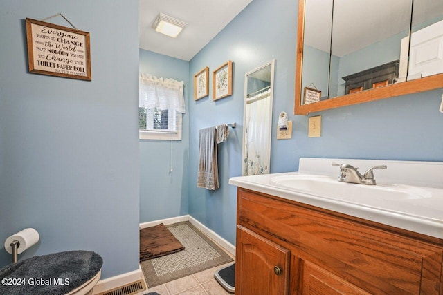 bathroom with tile flooring, toilet, and vanity