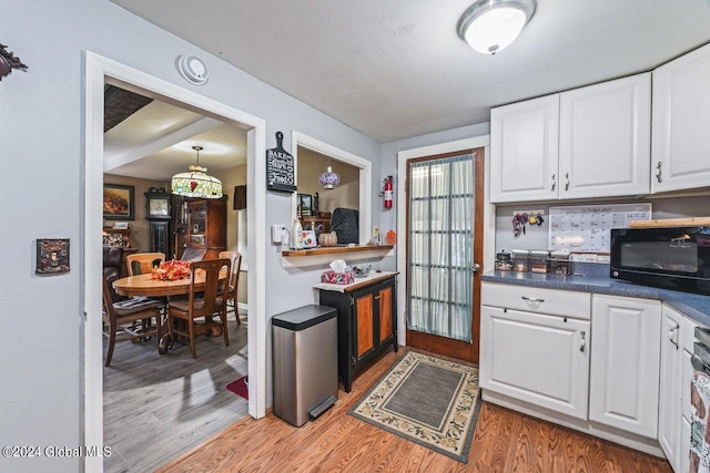 kitchen featuring white cabinets, decorative light fixtures, and light wood-type flooring