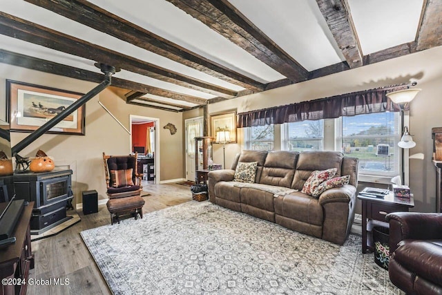 living room featuring a wood stove, light wood-type flooring, and beamed ceiling