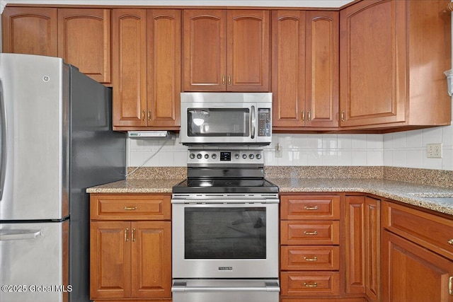 12 Lori Ln, Clifton Park, NY 12065 - kitchen featuring appliances with stainless steel finishes, decorative backsplash, brown cabinetry, and light stone countertops