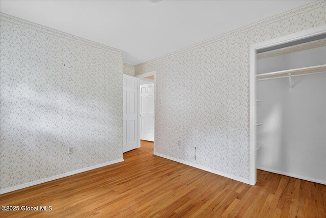 12 Lori Ln, Clifton Park, NY 12065 - unfurnished bedroom featuring wood finished floors, wallpapered walls, a closet, ornamental molding, and a walk in closet