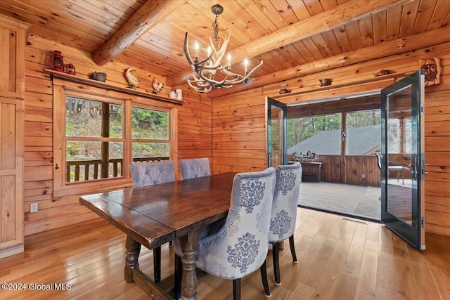 dining room featuring a notable chandelier, beam ceiling, a healthy amount of sunlight, and light hardwood / wood-style flooring