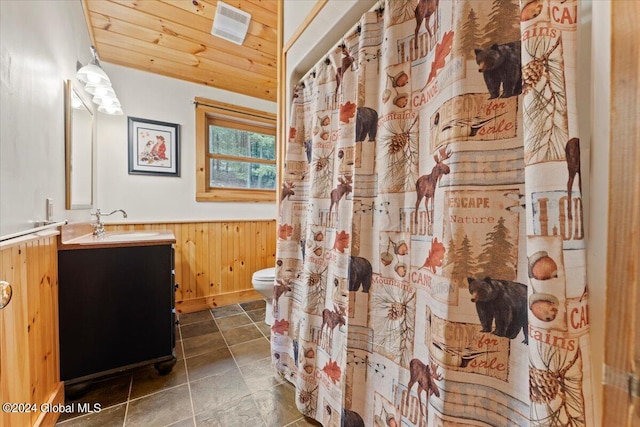 bathroom featuring wood walls, vanity, wood ceiling, and toilet