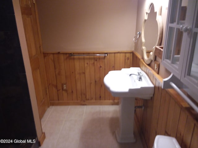 bathroom featuring tile patterned flooring, sink, and wood walls