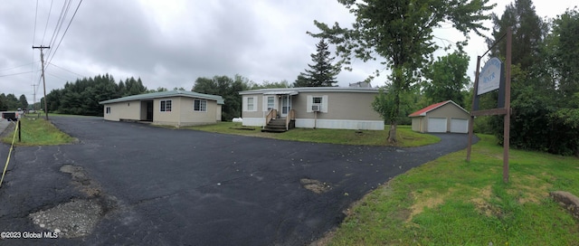 manufactured / mobile home with a garage, a front lawn, and an outdoor structure