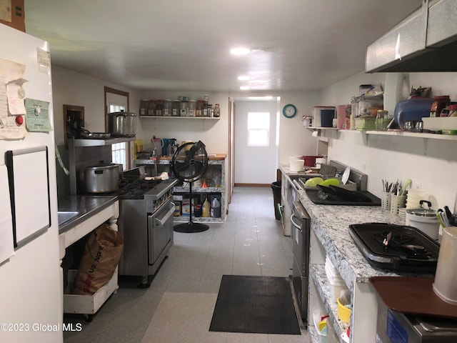 kitchen with dark tile flooring and stainless steel stove