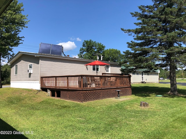 rear view of property featuring a deck and a lawn