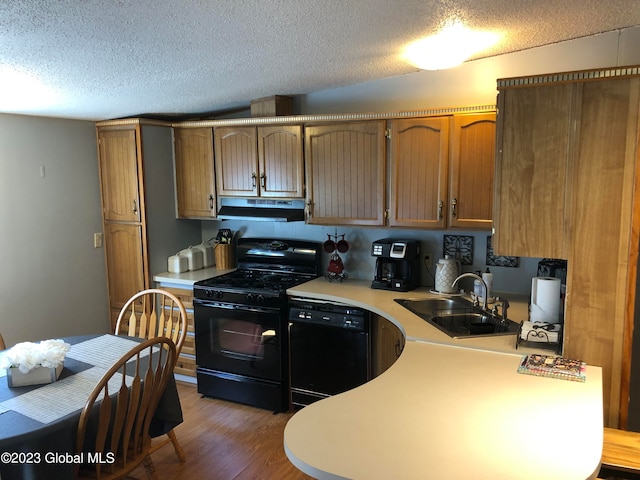 kitchen featuring a textured ceiling, sink, black appliances, and dark wood-type flooring