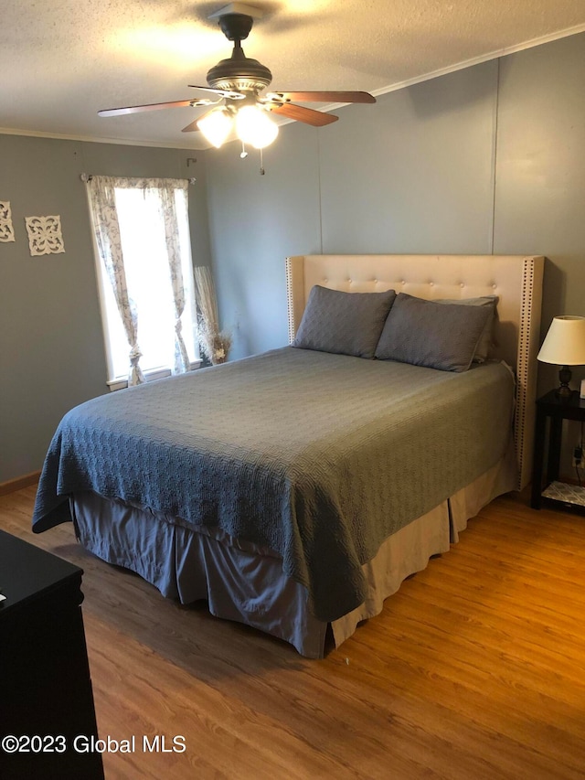 bedroom with hardwood / wood-style flooring, ceiling fan, and a textured ceiling